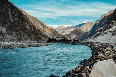 A turquoise river winding through a rocky valley toward snow-capped peaks in Ladakh