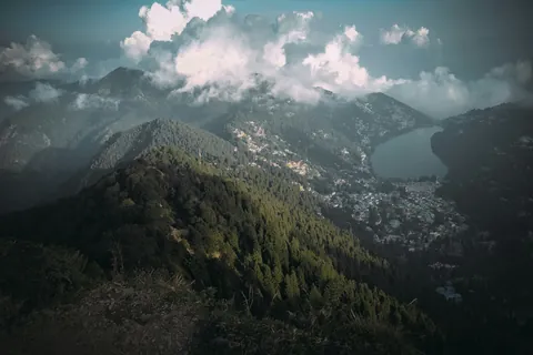 Naini Lake and the town of Nainital seen from a forested ridge under billowing cloud