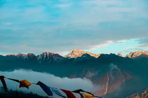 Snow-dusted Himalayan peaks at sunrise with prayer flags in the foreground, Tawang